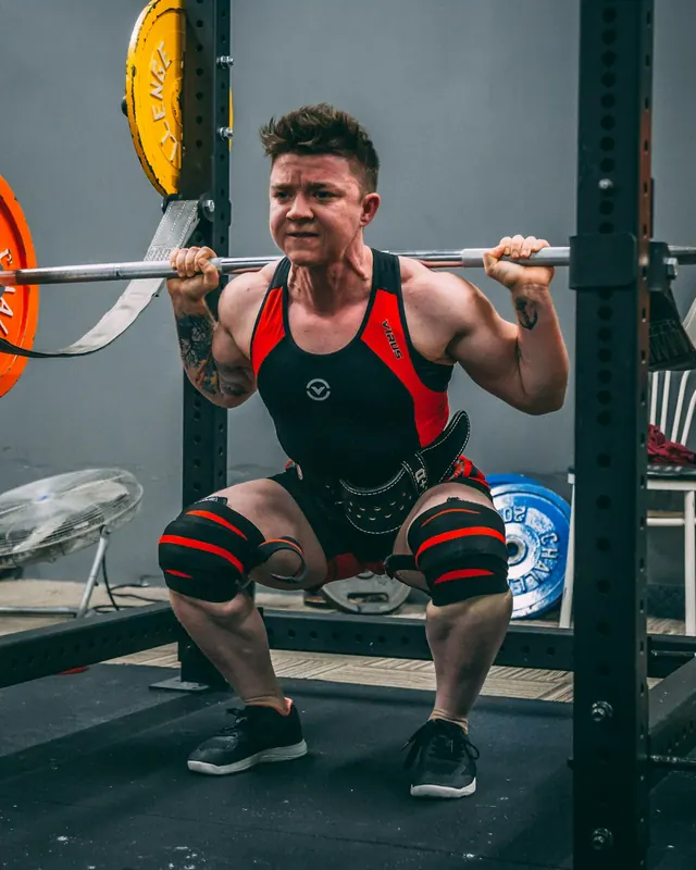 Atleta fazendo agachamento com barra no rack da academia