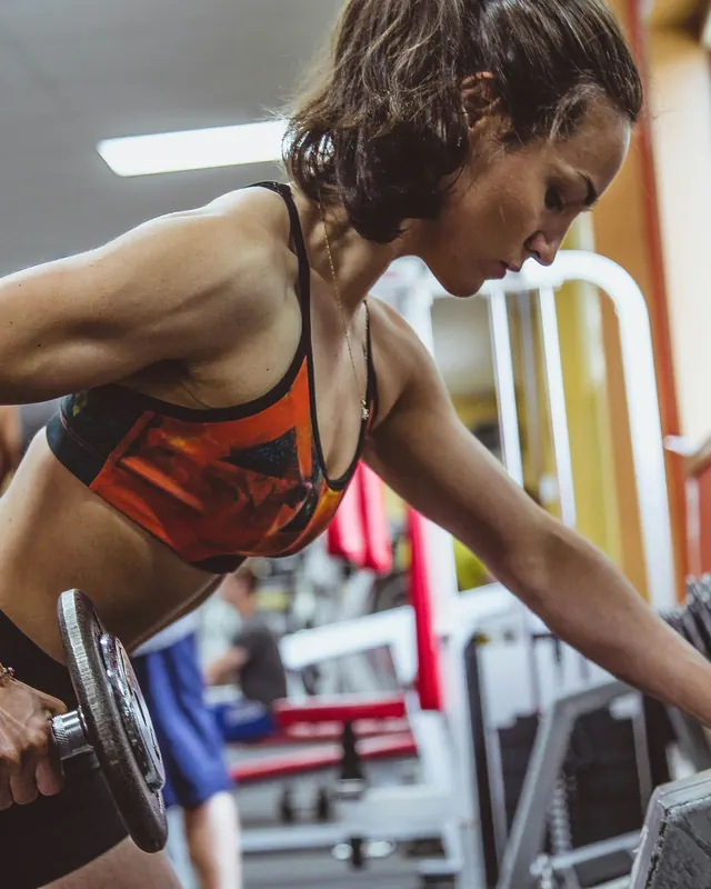 Mulher fazendo remada com halter na academia